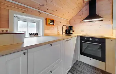 a kitchen with white cabinets and a black appliance at 2 Bedroom Cozy Home In Finnås in Grutle
