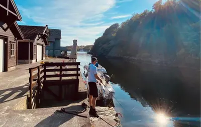 a man standing on a dock with a boat in the water at 2 Bedroom Cozy Home In Finnås in Grutle