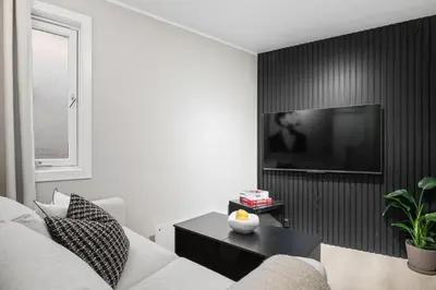 a living room with a couch and a tv on a wall at King bed - Renovated 2024 - 2BR Behind Bryggen in Bergen