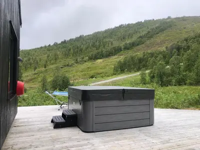 a large television sitting on a deck with a mountain at Cozy Nature Retreat, Danish Design w Jacuzzi option in Sogndal