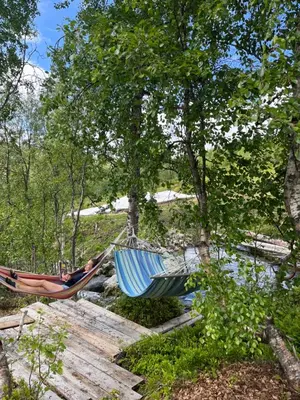 two hammocks sitting on a bridge next to a river at Cozy Nature Retreat, Danish Design w Jacuzzi option in Sogndal