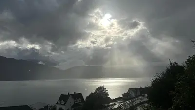 a cloudy sky over a body of water with houses at Sognefjorden View in Leikanger
