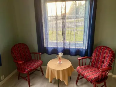 two chairs and a table in a room with a window at Heinåli apartment in Isfjorden
