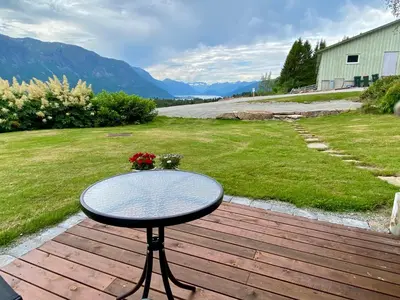 a table on a deck with a view of a yard at Heinåli apartment in Isfjorden