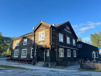 an old wooden building on the corner of a street at Bokhandel'n Gjestehus in Vågåmo