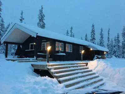 a log cabin in the snow with lights on at Hytta for 8 personer skiut/inn in Trysil