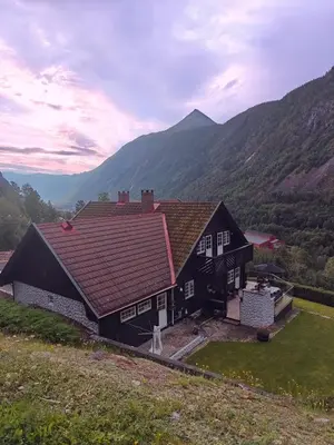 a black house with a red roof in the mountains at Fritt beliggende stor enebolig med høy standard in Rjukan