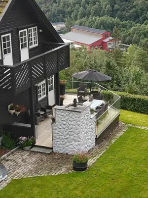 a black house with a patio and an umbrella at Fritt beliggende stor enebolig med høy standard in Rjukan