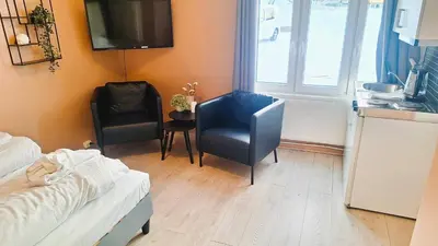 a room with a bed and two chairs and a kitchen at Sentrumsnær leilighet - K1 in Lillehammer