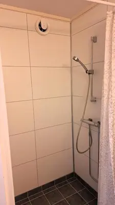 a shower with a shower head in a bathroom at Sentrumsnær leilighet - K1 in Lillehammer