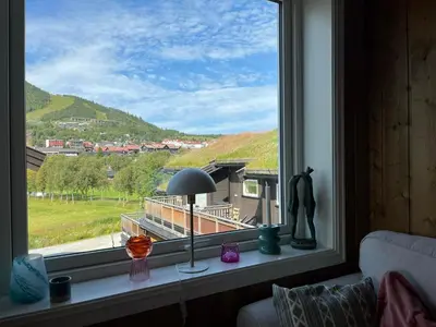 a window with a lamp and a view of a house at Sentral leilighet på Geilo in Geilo