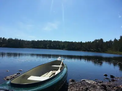 a boat sitting on the shore of a lake at Stabburet på Balsnes Gård in Hitra