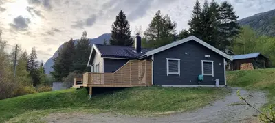 a black house with a deck on a hill at Hus i flott natur in Skjåk