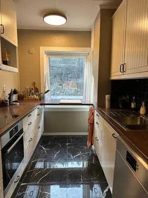 a kitchen with a black floor and a window at Leilighet med nydelig utsikt over Bergen in Bergen