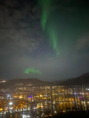 a view of a city at night with green northern lights at Leilighet med nydelig utsikt over Bergen in Bergen
