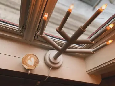 a chandelier hanging from a window with a cup of coffee at Bed and Brunsj, Sand in Sand