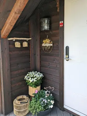 a wooden house with baskets and flowers on a porch at Svært nydelig fritidshytte in Forland