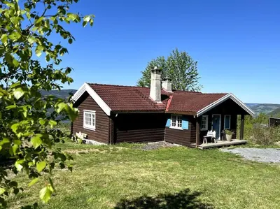 a small house with a porch on a grass field at Koselig hytte 10 minutter fra Lillehammer sentrum in Lillehammer