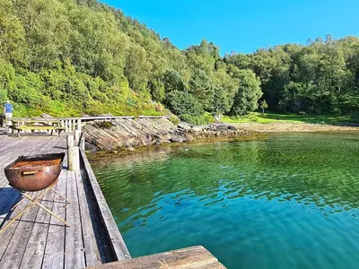 a wooden dock with a boat on the water at 8 person holiday home in Masfjordnes-By Traum in Masfjorden