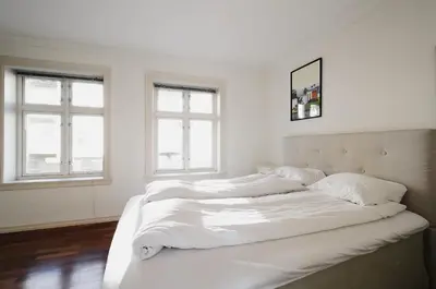 a white bedroom with two beds and two windows at The View - BIG Apartment in City Center in Bergen