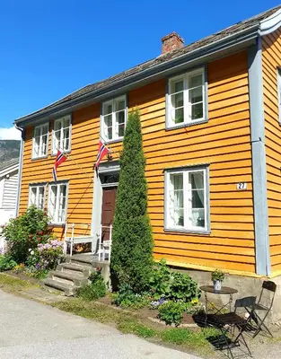 a yellow house with a table and chairs in front of it at Kvammehuset på Gamle Lærdalsøyri in Lærdalsøyri