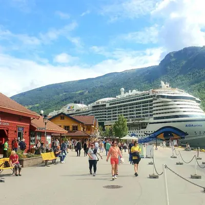a cruise ship is docked next to a street with people at Kvammehuset på Gamle Lærdalsøyri in Lærdalsøyri
