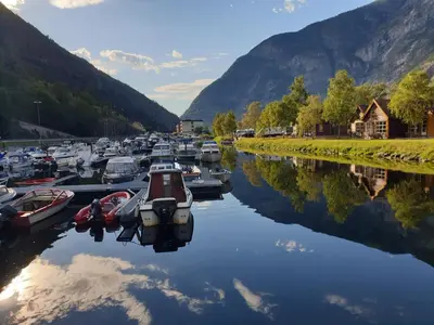a group of boats are docked in a river at Kvammehuset på Gamle Lærdalsøyri in Lærdalsøyri