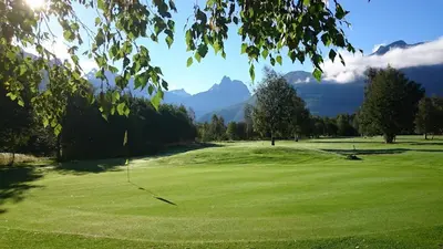 a green golf course with mountains in the background at Bakkebo Rampestreken in Åndalsnes