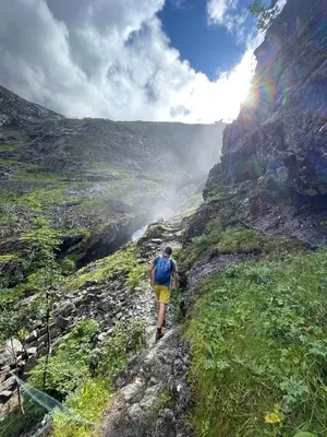 a man walking up a mountain with a rainbow in the background at Bakkebo Rampestreken in Åndalsnes
