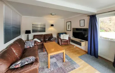 a living room with a leather couch and a tv at 4 Bedroom Awesome Home In Nedre Vats in Stokka
