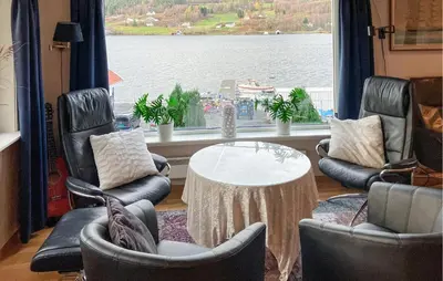 a living room with chairs and a table and a large window at 4 Bedroom Awesome Home In Nedre Vats in Stokka