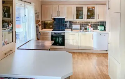 a kitchen with white cabinets and a wooden floor at 4 Bedroom Awesome Home In Nedre Vats in Stokka