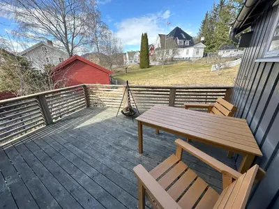 a wooden deck with a picnic table and two chairs at Stort hus sentralt i Lillehammer in Lillehammer