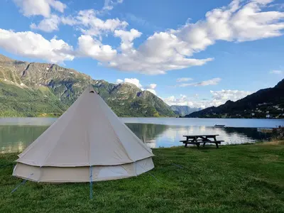a tent and a picnic table next to a lake at Dalsøren Camping og hytter in Luster