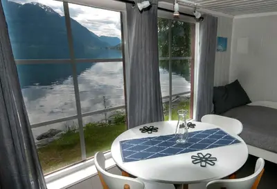 a table and chairs in front of a large window at Dalsøren Camping og hytter in Luster