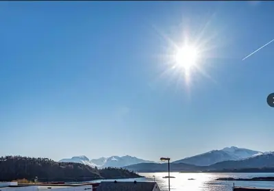 a sun shining over a body of water with mountains at Moderne rekkehus, god standard. in Ålesund