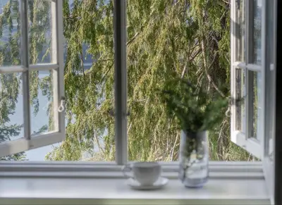 a vase sitting on a window sill with a cup at Vertshuset Konow in Bergen