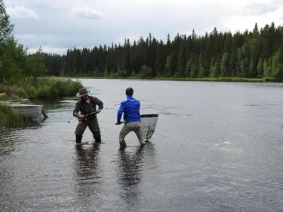 two men are standing in the water in a river at Rena Hostel in Rena