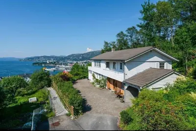 a white house on a hill next to the water at Spacious villa with view - 5BR - FREE parking - Great Wi-Fi in Bergen