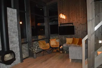 a living room with a couch and chairs and a television at Pow Panorama - High standard Mountain home in Sogndal