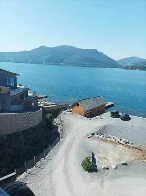 a dirt road next to a large body of water at Sveciu namai in Sandeid