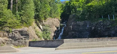 a waterfall on the side of a mountain next to a road at Sveciu namai in Sandeid