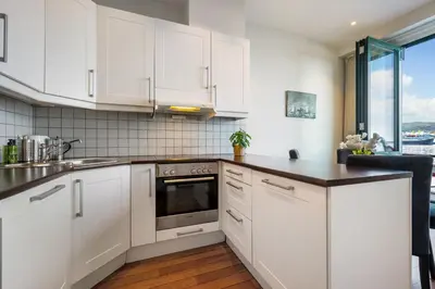 a kitchen with white cabinets and a counter top at New! Sea front apt. with terrace above the sea! in Bergen