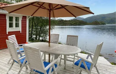 a table and chairs with an umbrella on a deck at Amazing Home In Eiksund With Kitchen in Eiksund