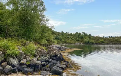 a river with rocks and trees on the shore at Amazing Home In Eiksund With Kitchen in Eiksund