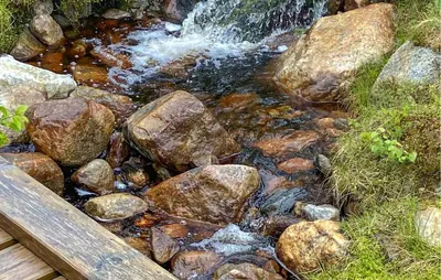 a stream of water with rocks and a wooden bench at Amazing Apartment In Noresund With Wifi in Noresund