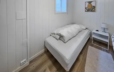 a small white room with a bed and a table at Awesome Home In Noresund With Wifi in Noresund