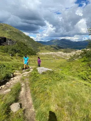 two people walking on a trail on a grassy hill at Kvamskogen & Hardanger Holliday homes in Norheimsund