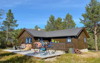 a large wooden cabin with a deck and chairs at 4 Bedroom Gorgeous Home In Bjorli in Bjorli