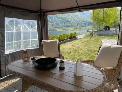 a table in a tent with a view of a lake at Stryn Golden Resort-«Skulehuset» in Stryn